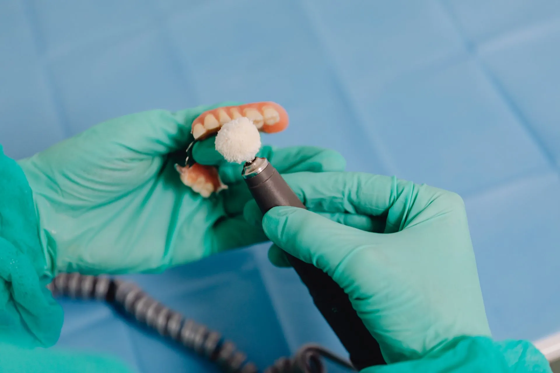 Pulido de una prótesis dental con guantes en la Clínica Dental Cendón