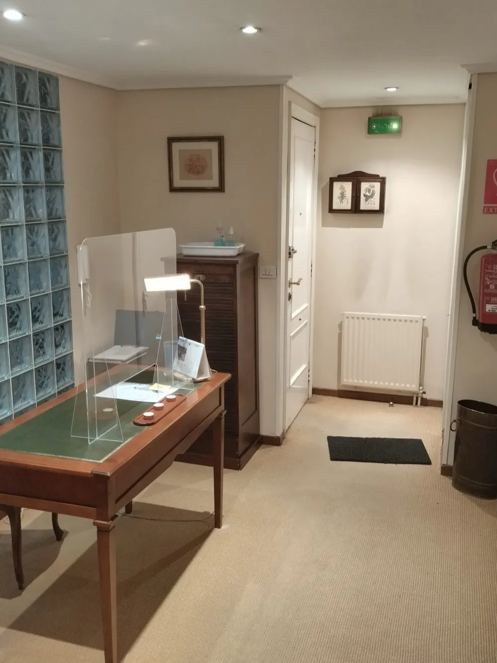 Recepción de la Clínica Dental Cendón con mesa de madera y pared de pavés